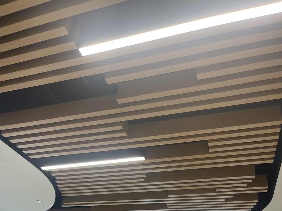 Layered wood-look baffle ceiling with linear lighting